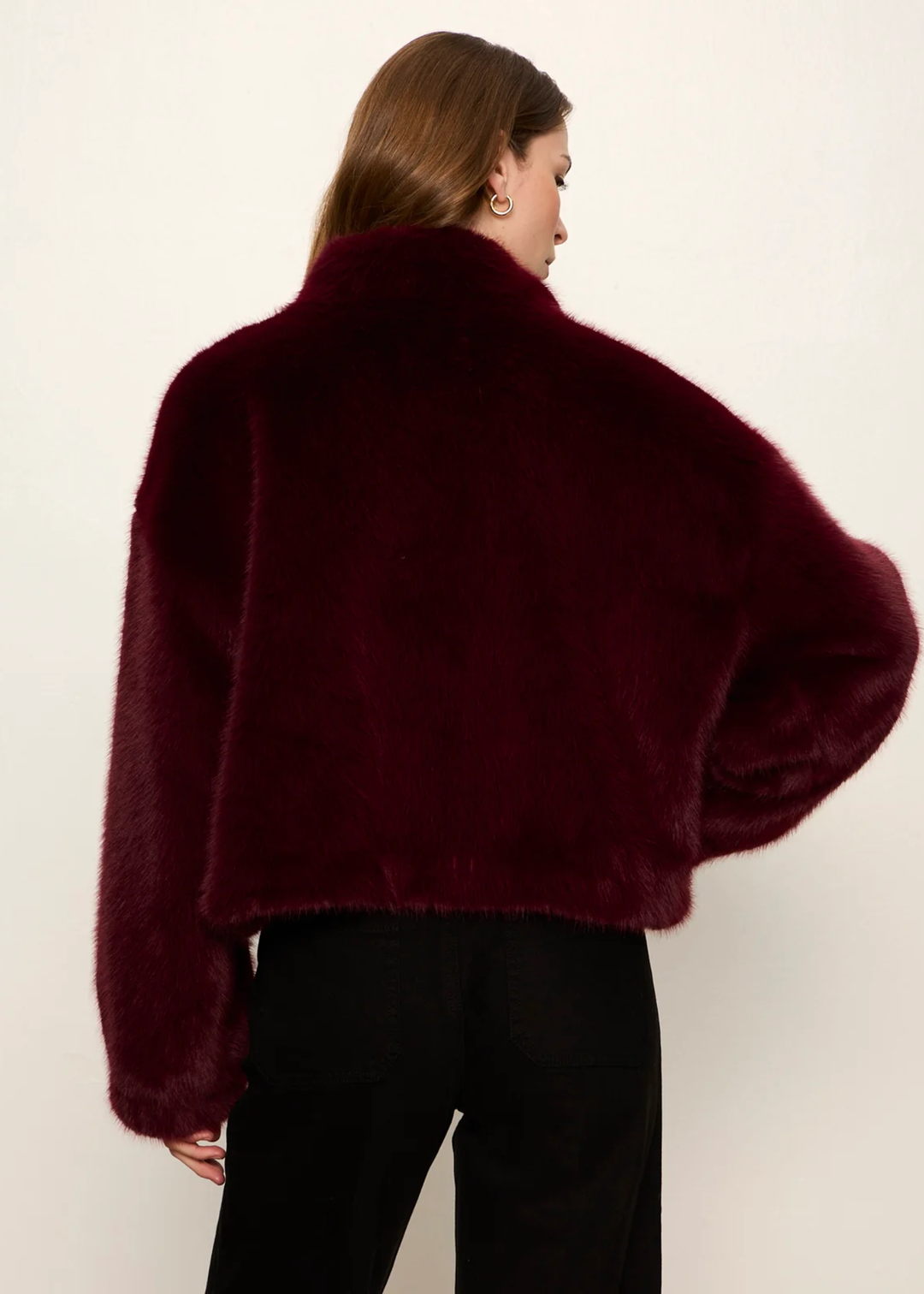 A woman wearing a maroon fur jacket.