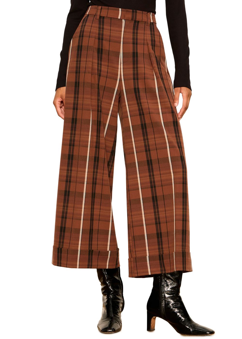 A model wearing high-waisted, wide-leg cropped trousers in a rust brown and black plaid pattern with white vertical stripe accents, styled with a black long-sleeve top and black leather ankle boots.