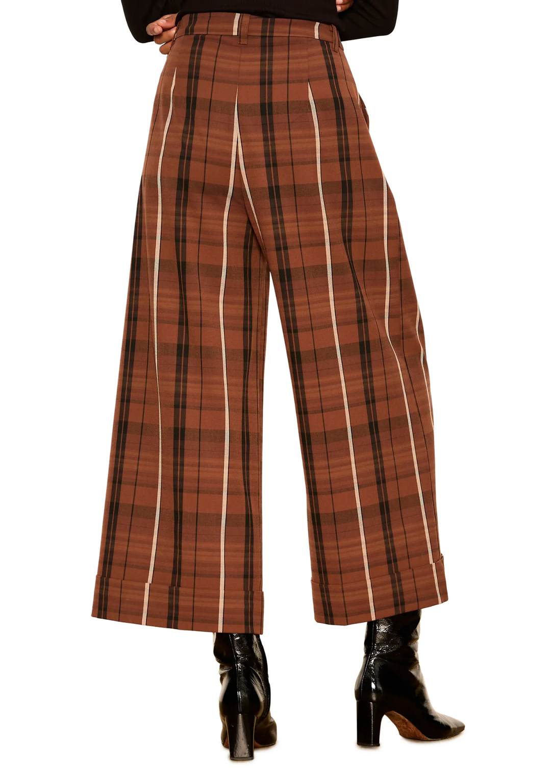 A person wearing high-waisted wide-leg plaid trousers in rust brown, black, and cream, paired with black heeled ankle boots, shown from the waist down on a white background.