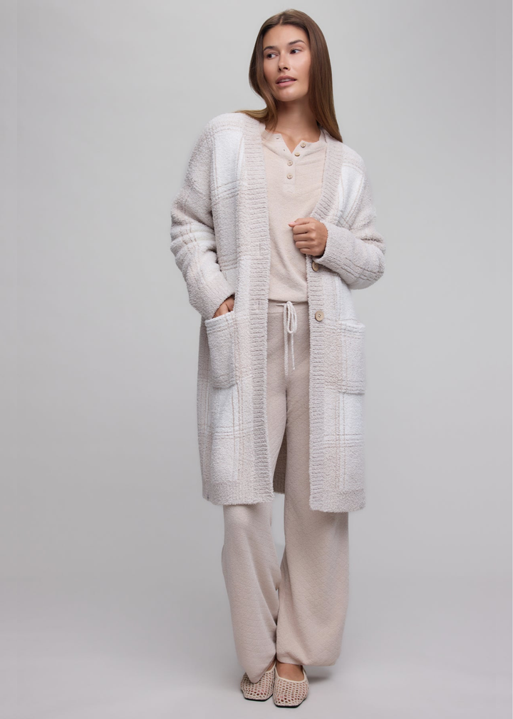 Woman wearing a stone plaid long cardigan over a tan matching set.
