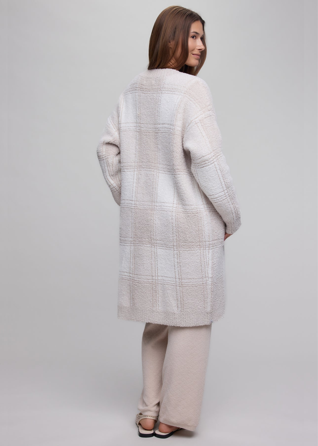 Woman wearing a stone plaid long cardigan over a tan matching set.