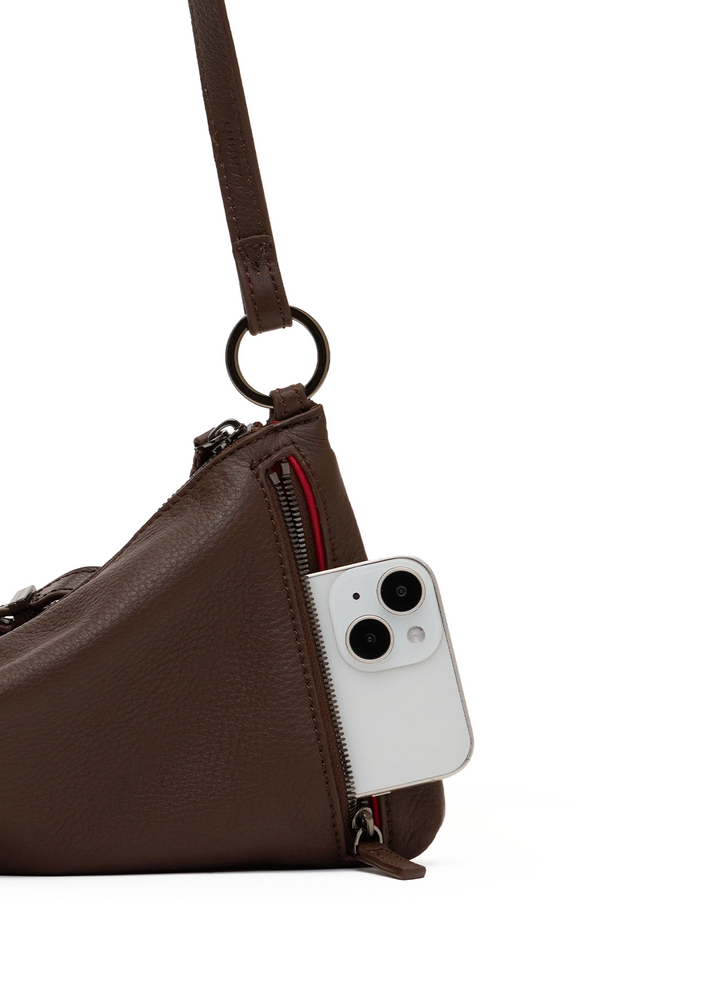 A close-up of a brown pebbled leather shoulder bag with a white smartphone partially tucked into a side zipper pocket, shown on a clean white background.