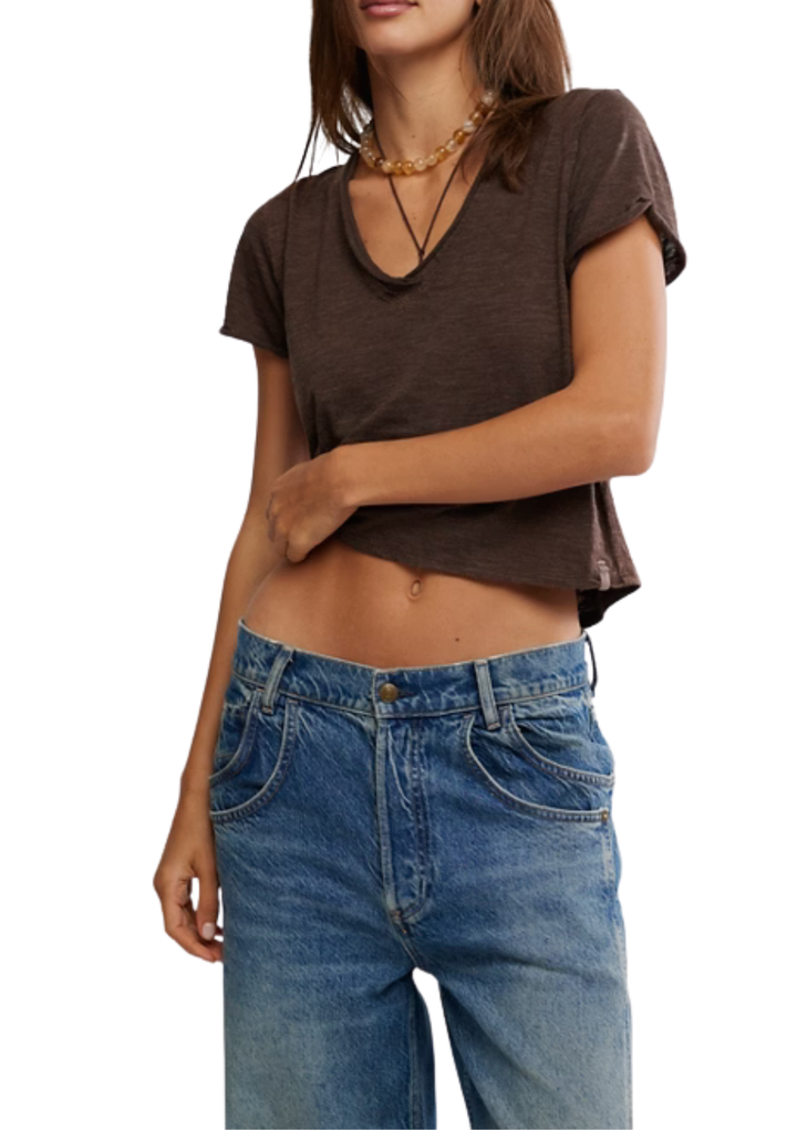 Person wearing a brown crop top and blue jeans on a white background