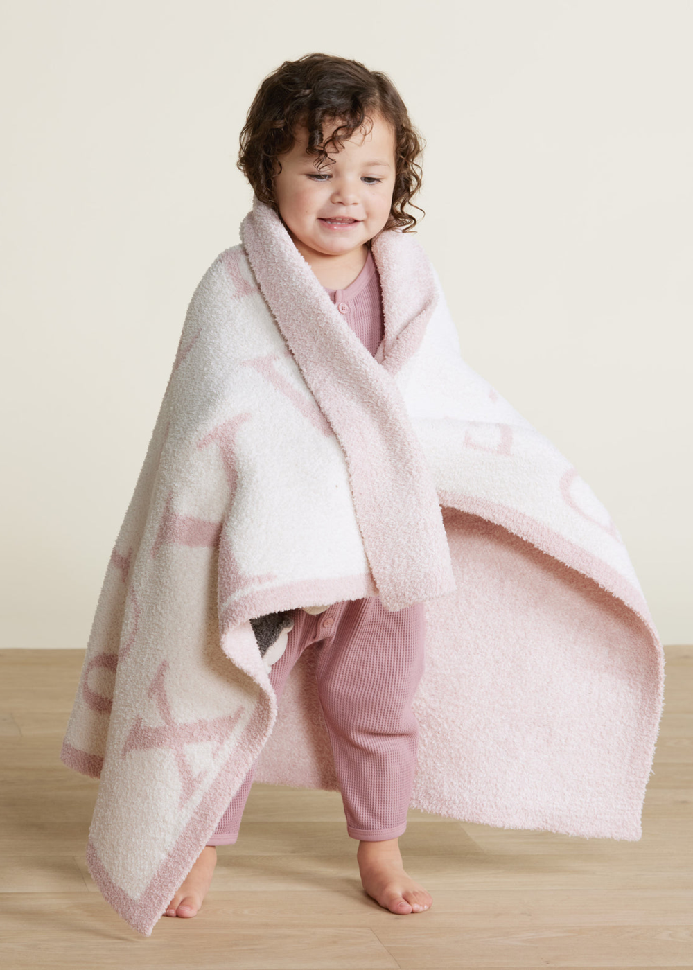 Girl holding a pink and white ABC patterned blanket