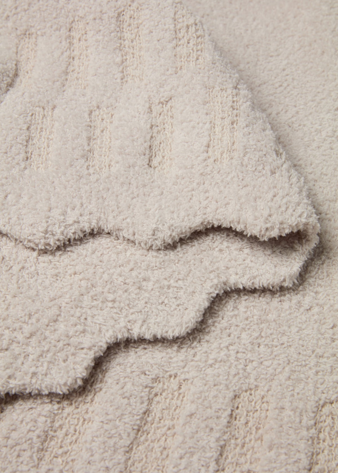 Cream blanket with scalloped edges laying folded