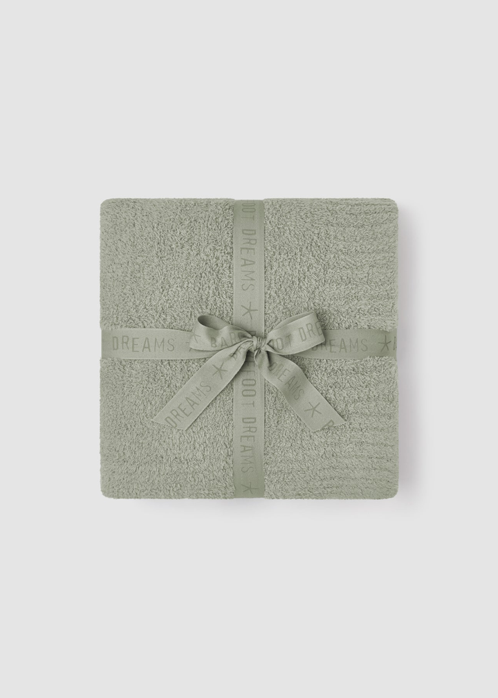 Green blanket folded and tied with a green bow sitting on a grey background
