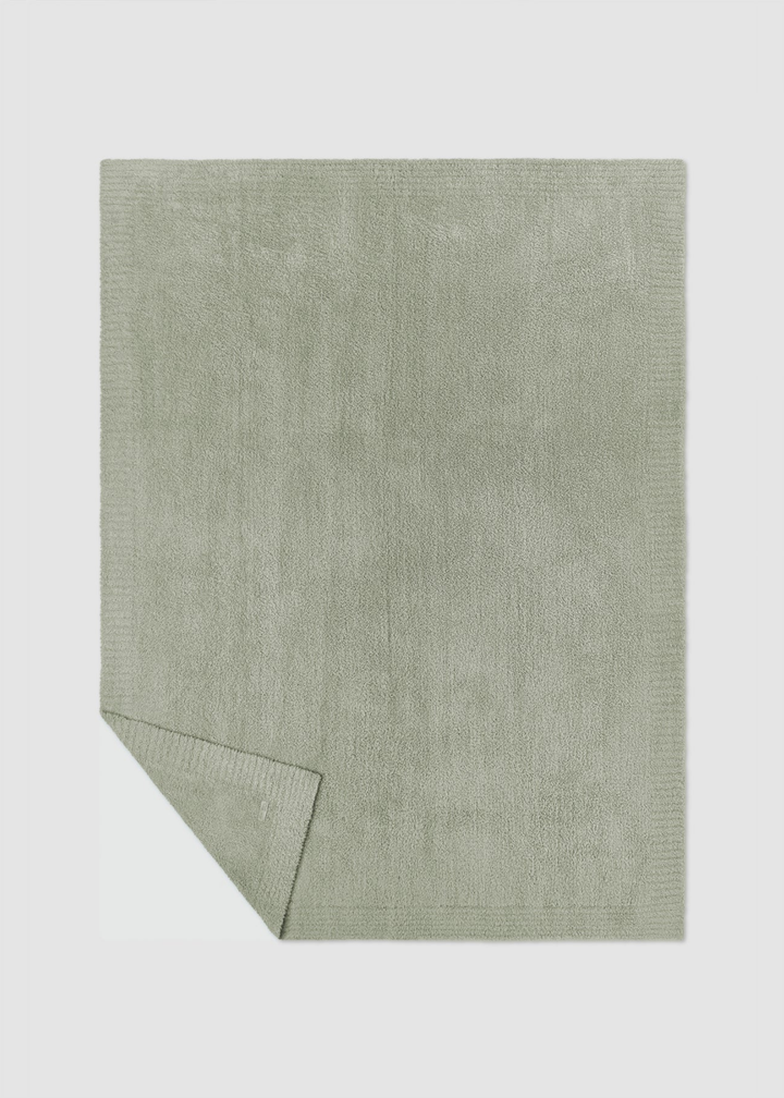 Green blanket laying on a gray background with a corner folded