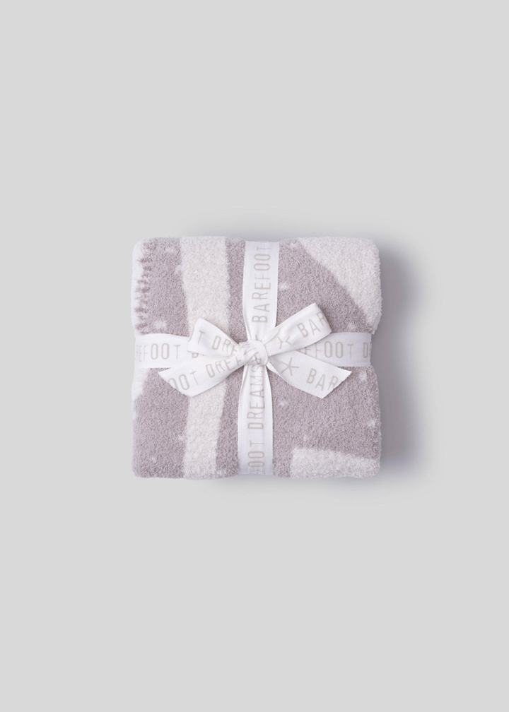 Folded pink and cream blanket with a white bow on a white background