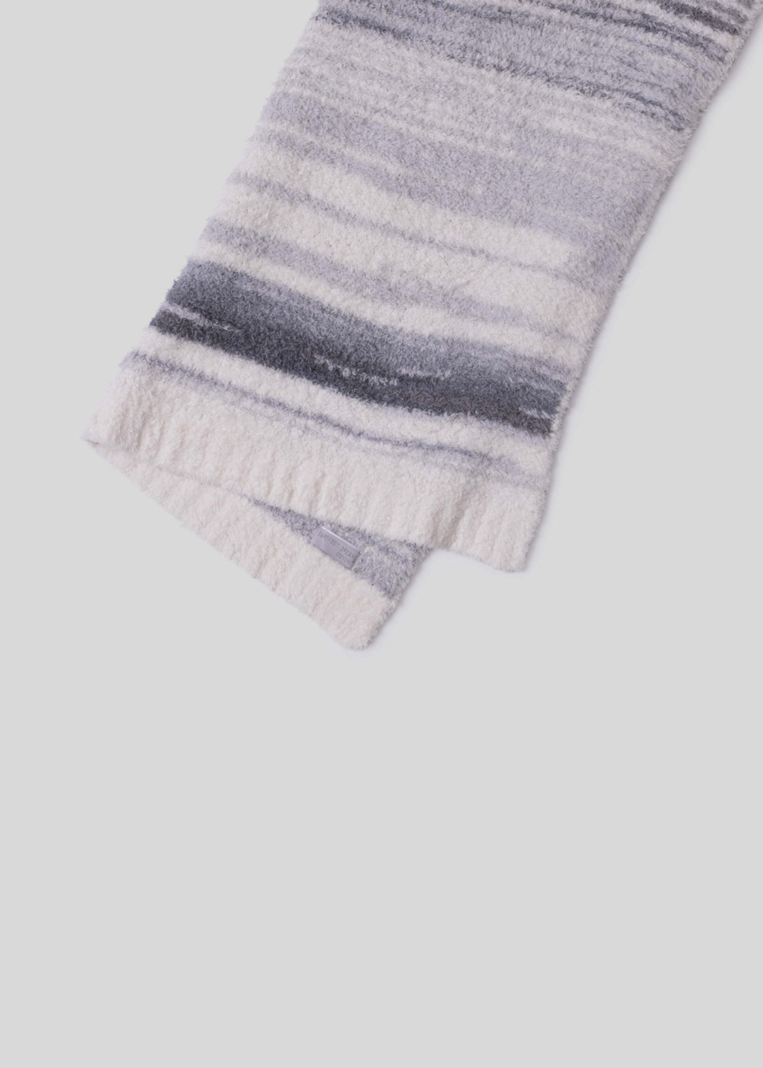 Blue, grey, and cream striped blanket laying on a white background folded in half