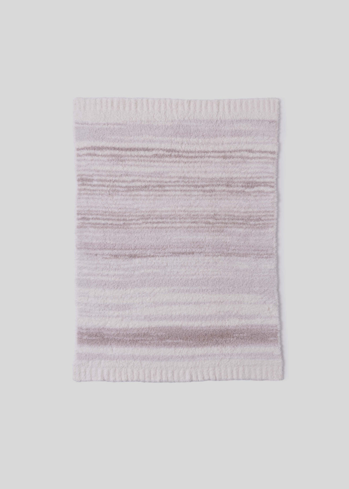 Pink and cream striped blanket laying on a white background