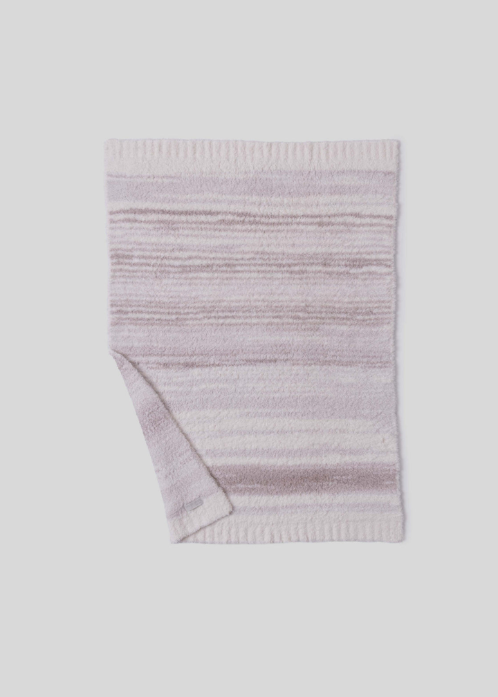 Pink and cream striped blanket with a corner folded laying on a white background 