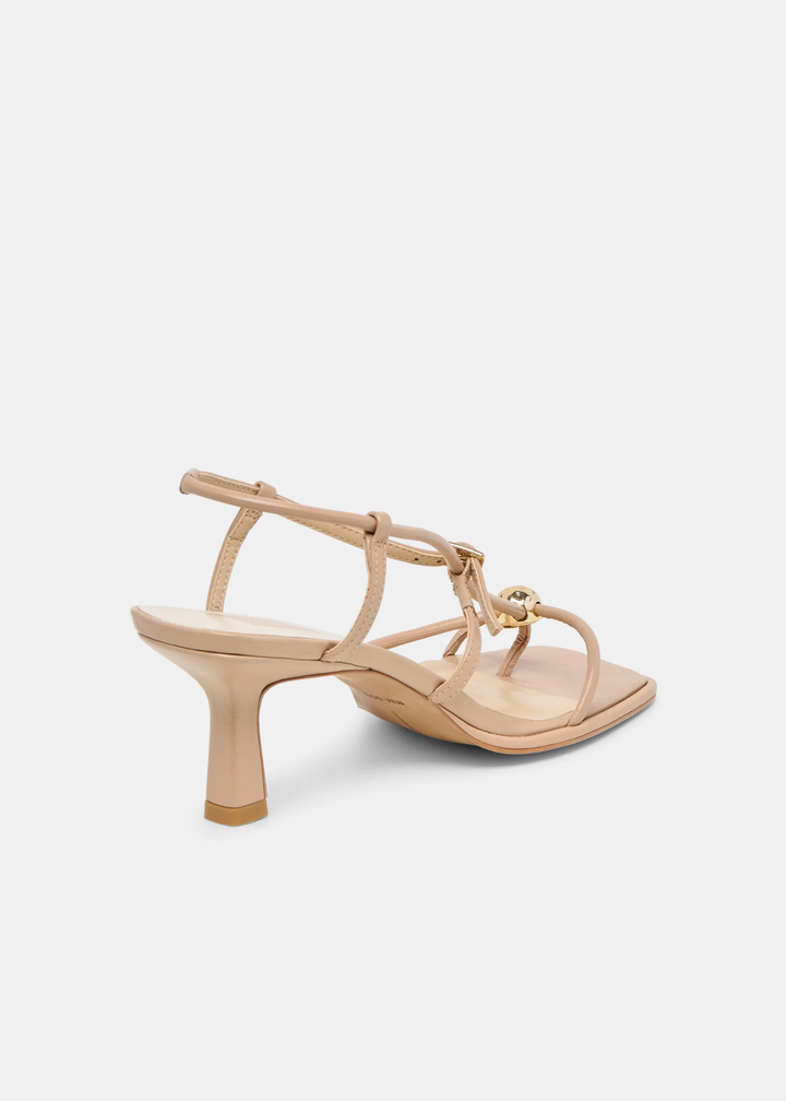 Back view of tan strappy heels with a gold button against a white background