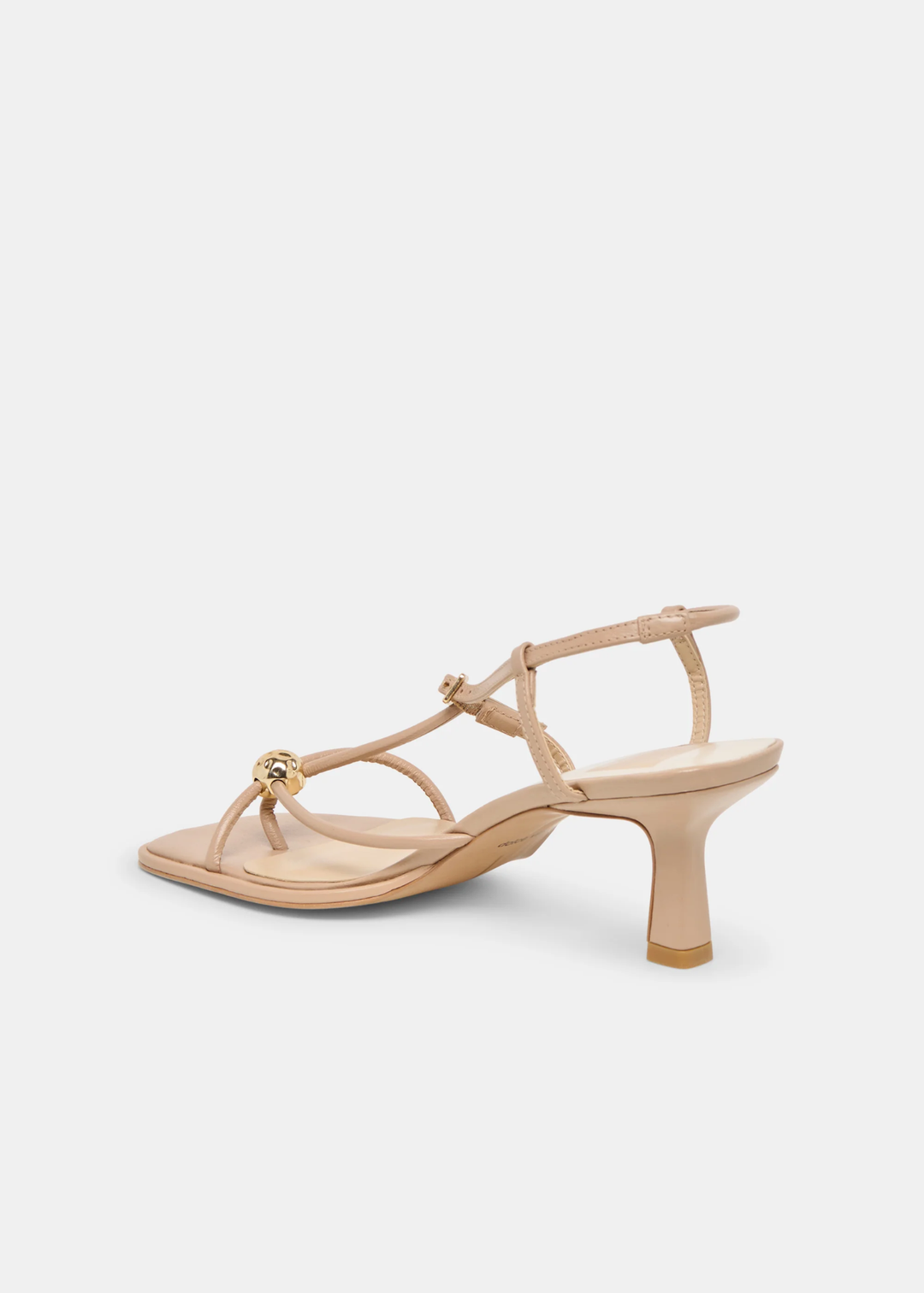 Side view of tan strappy heels with a gold button against a white background