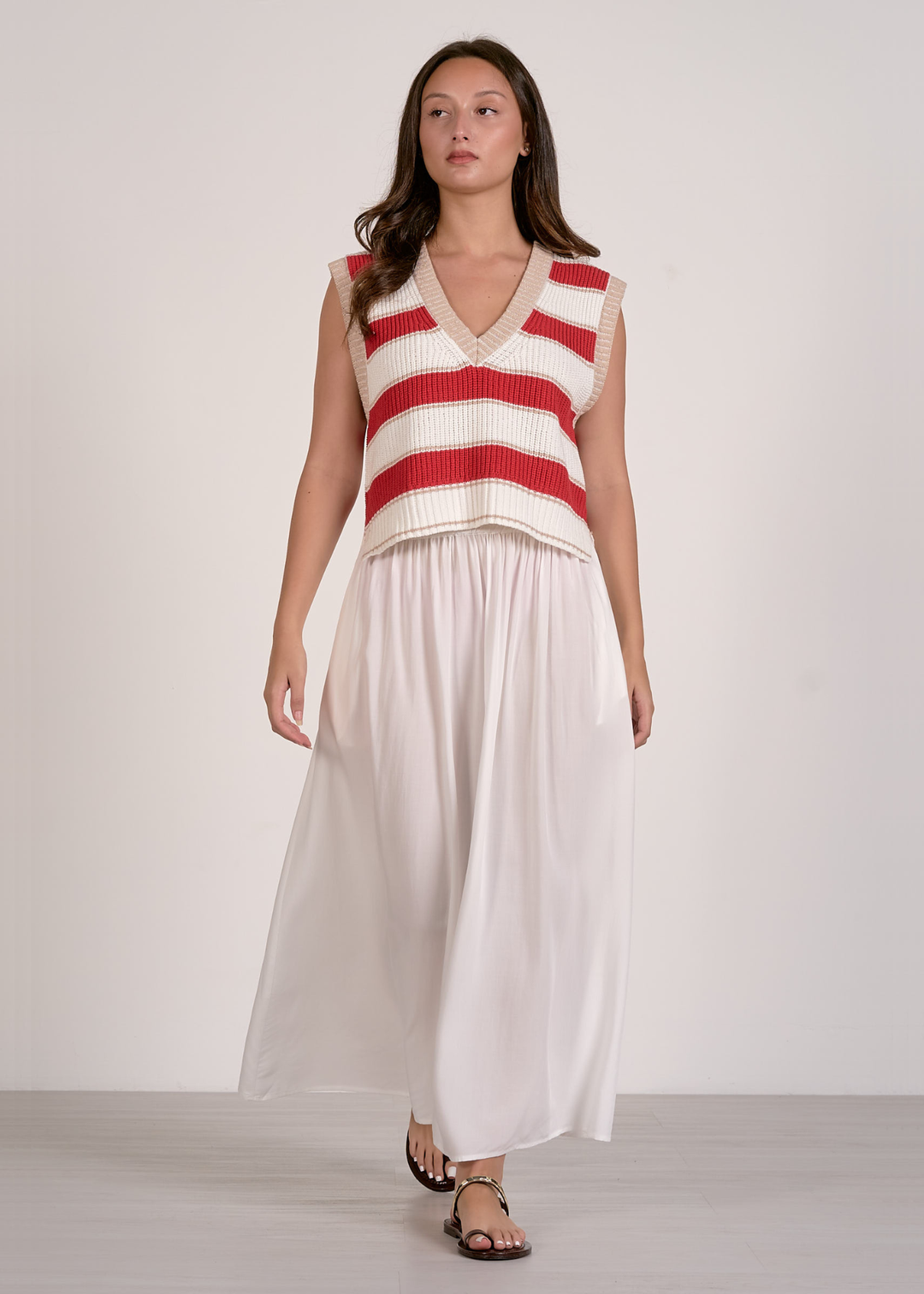 Woman wearing a red and white striped sweater vest and a white skirt