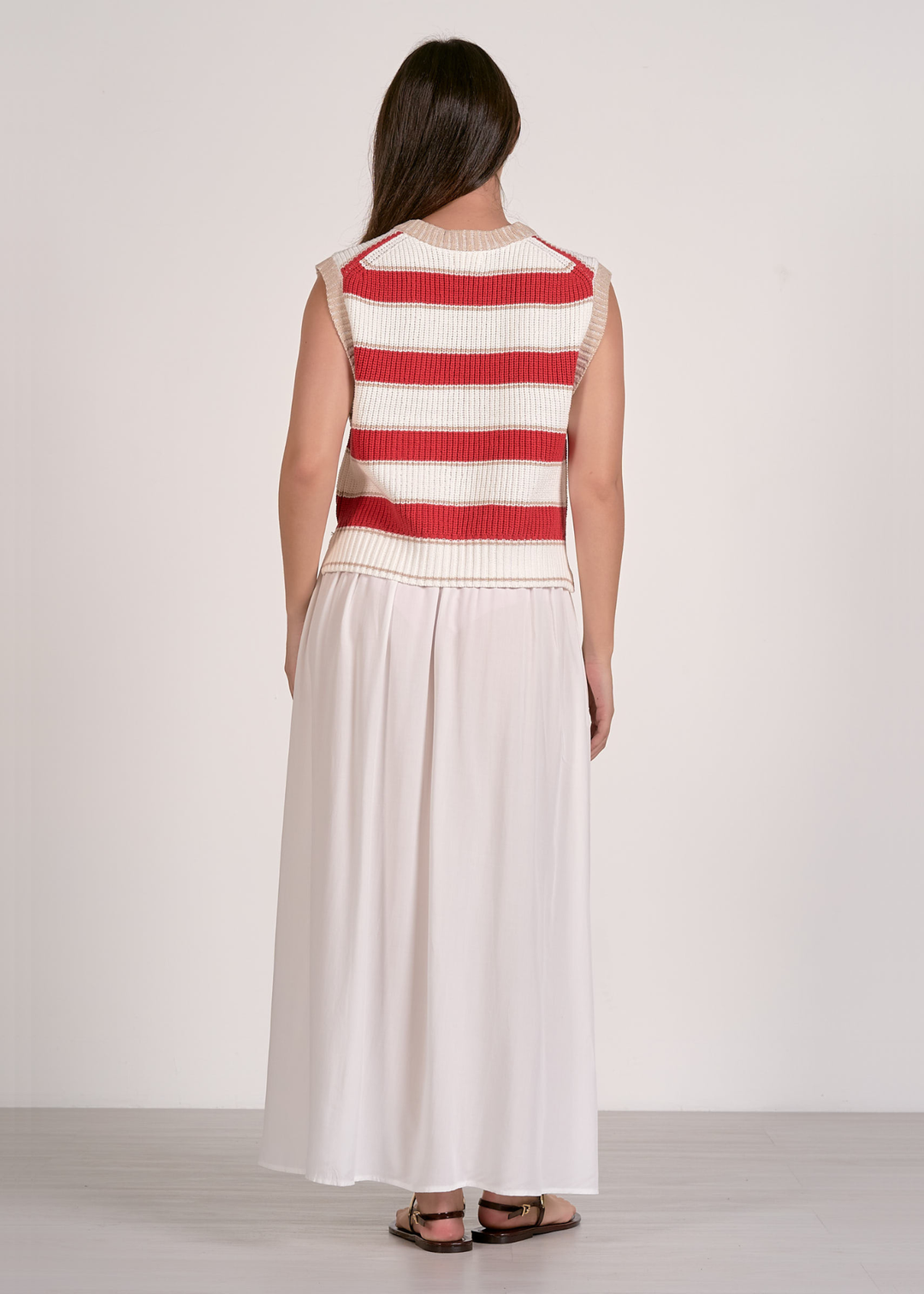Woman wearing a red and white striped sweater vest and a white skirt