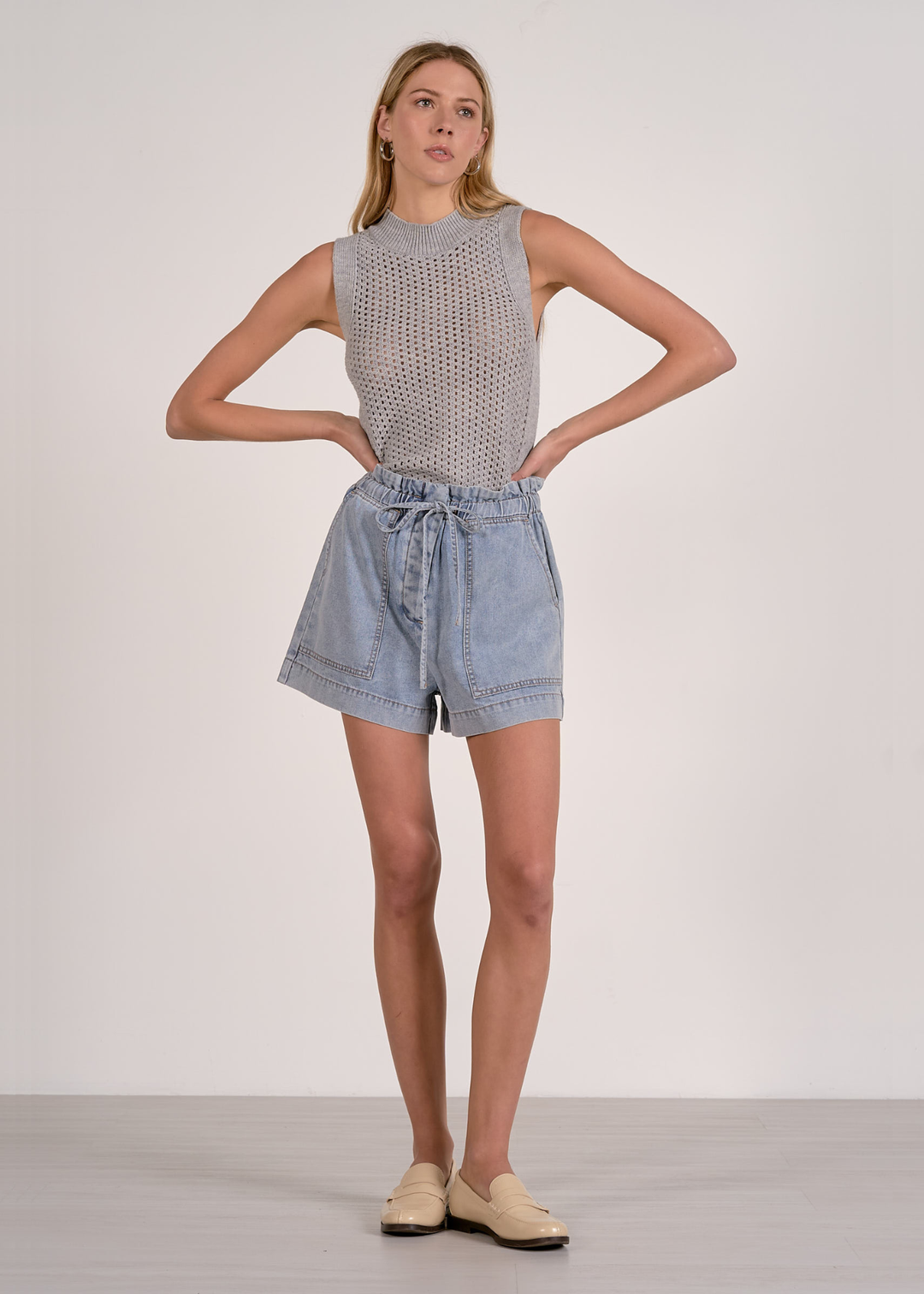 Woman wearing blue shorts with a grey knit tank
