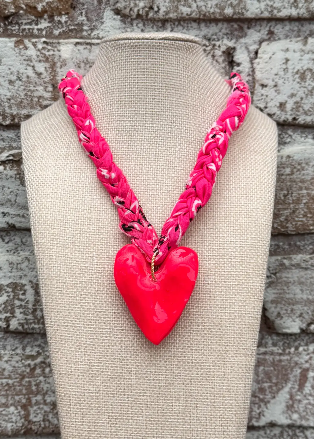 Hot pink bandana necklace with a large hot pin heart charm on a display