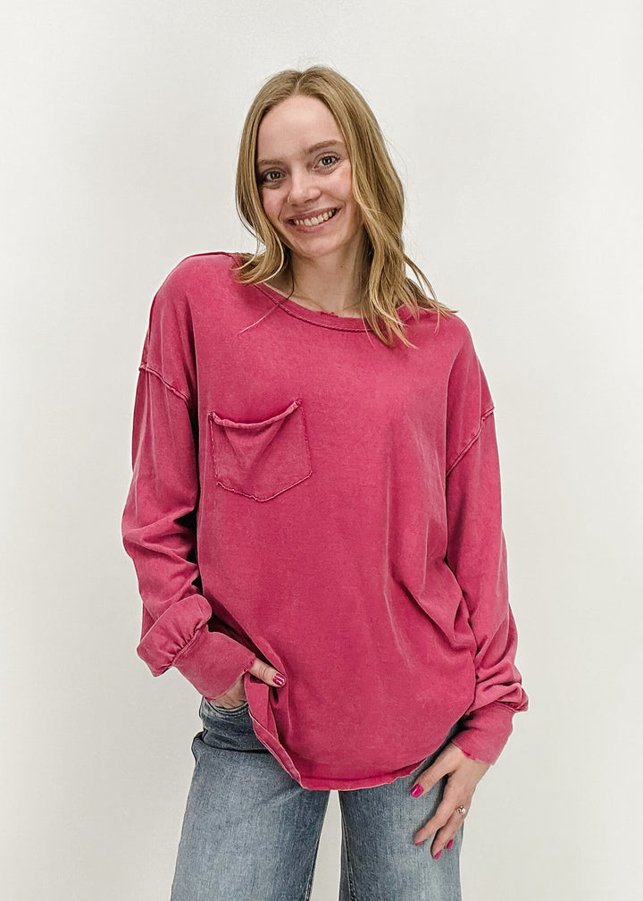 A woman wearing the Free People Fade Into You Tee in Vivacious, a loose-fit long-sleeve casual top, styled with light-wash jeans for a relaxed, laid-back look.