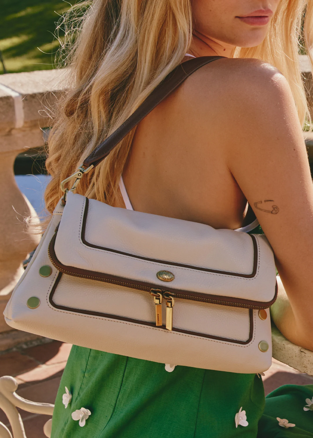 Woman holding a white leather purse with brown trim and gold accents