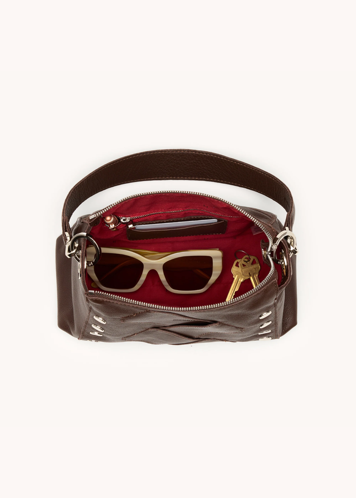 Brown leather woven purse with silver hardware on a white background open with a red lining