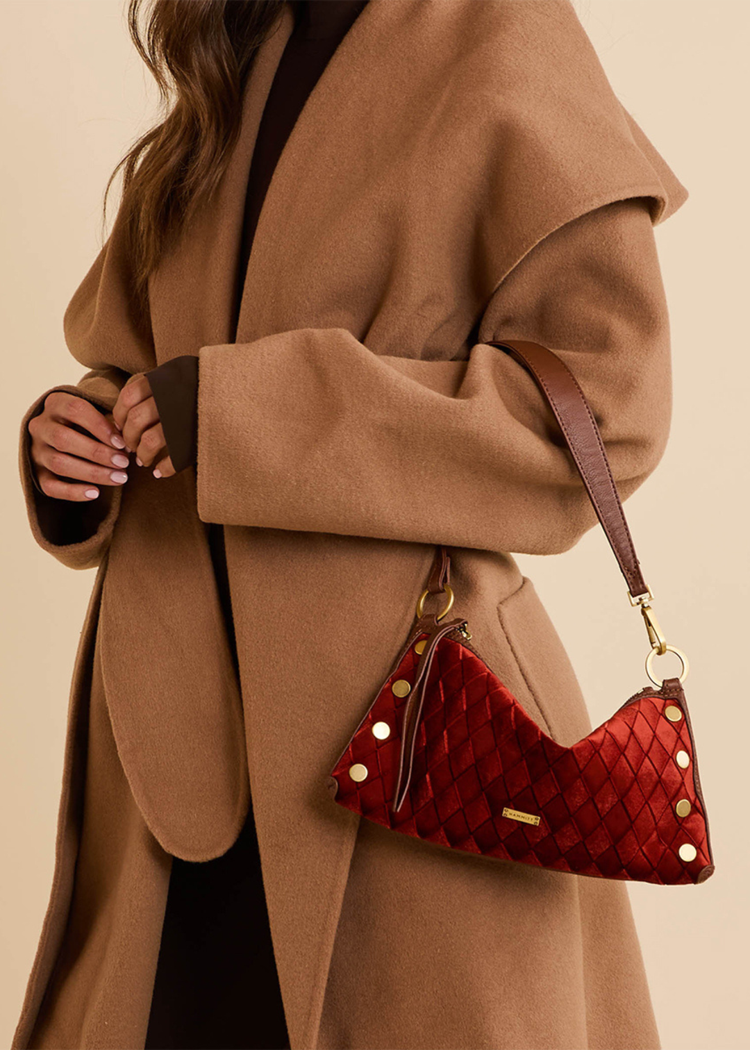 Woman wearing a brown coat and holding a red velvet and brown leather purse with gold accents
