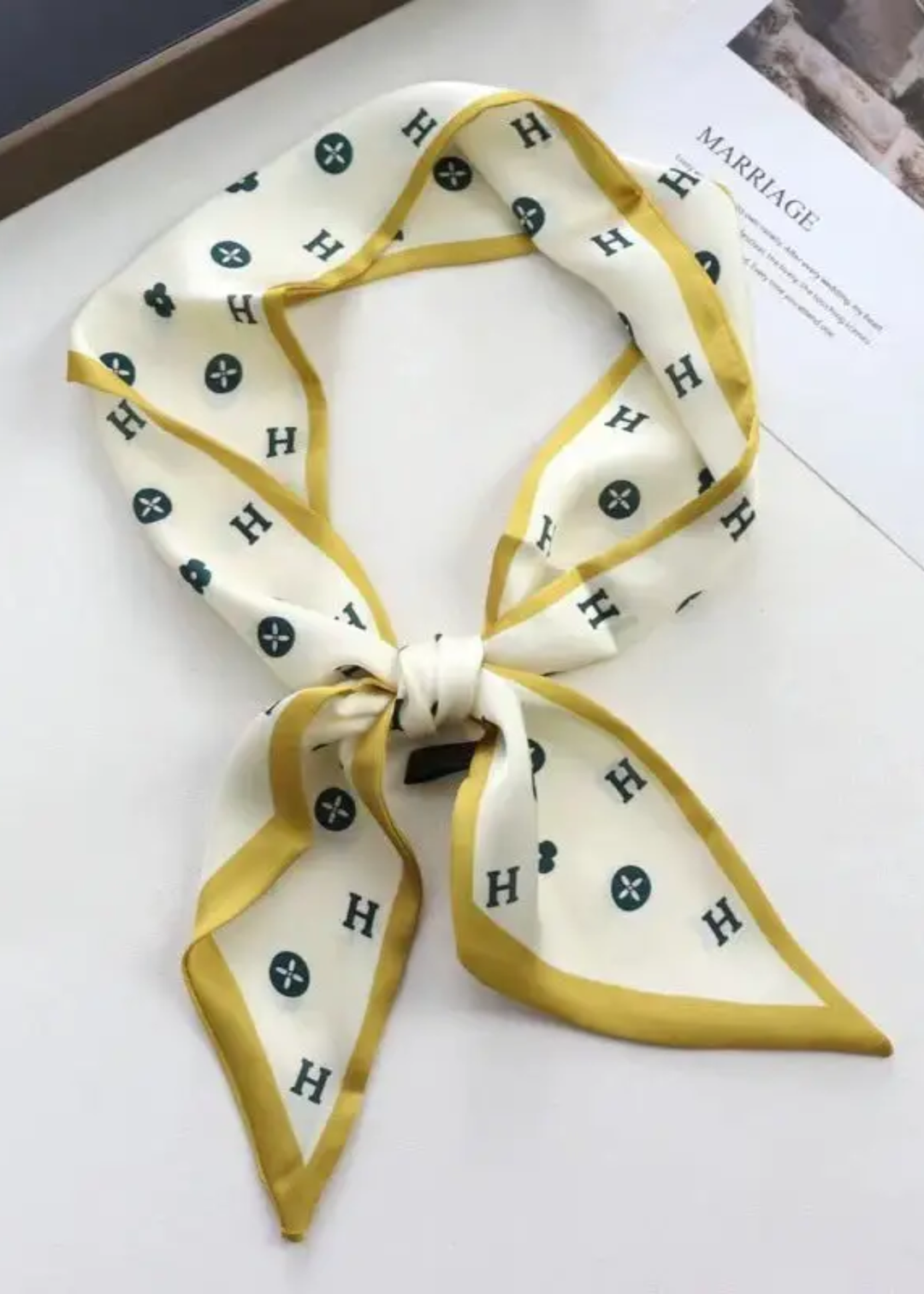 Cream scarf with a black H pattern and yellow trim