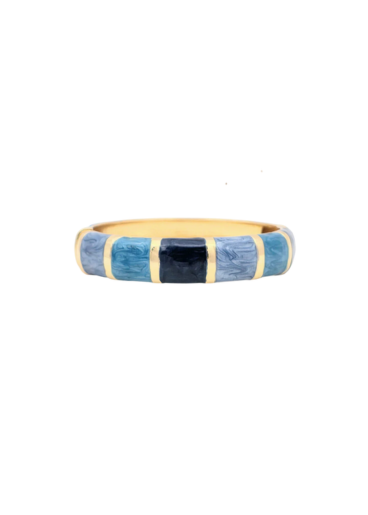 Gold framed bangle bracelet with blue enamel squares on a white background