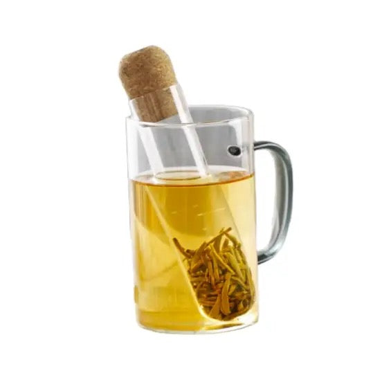 Clear mug with yellow liquid and a tea bag on a white background