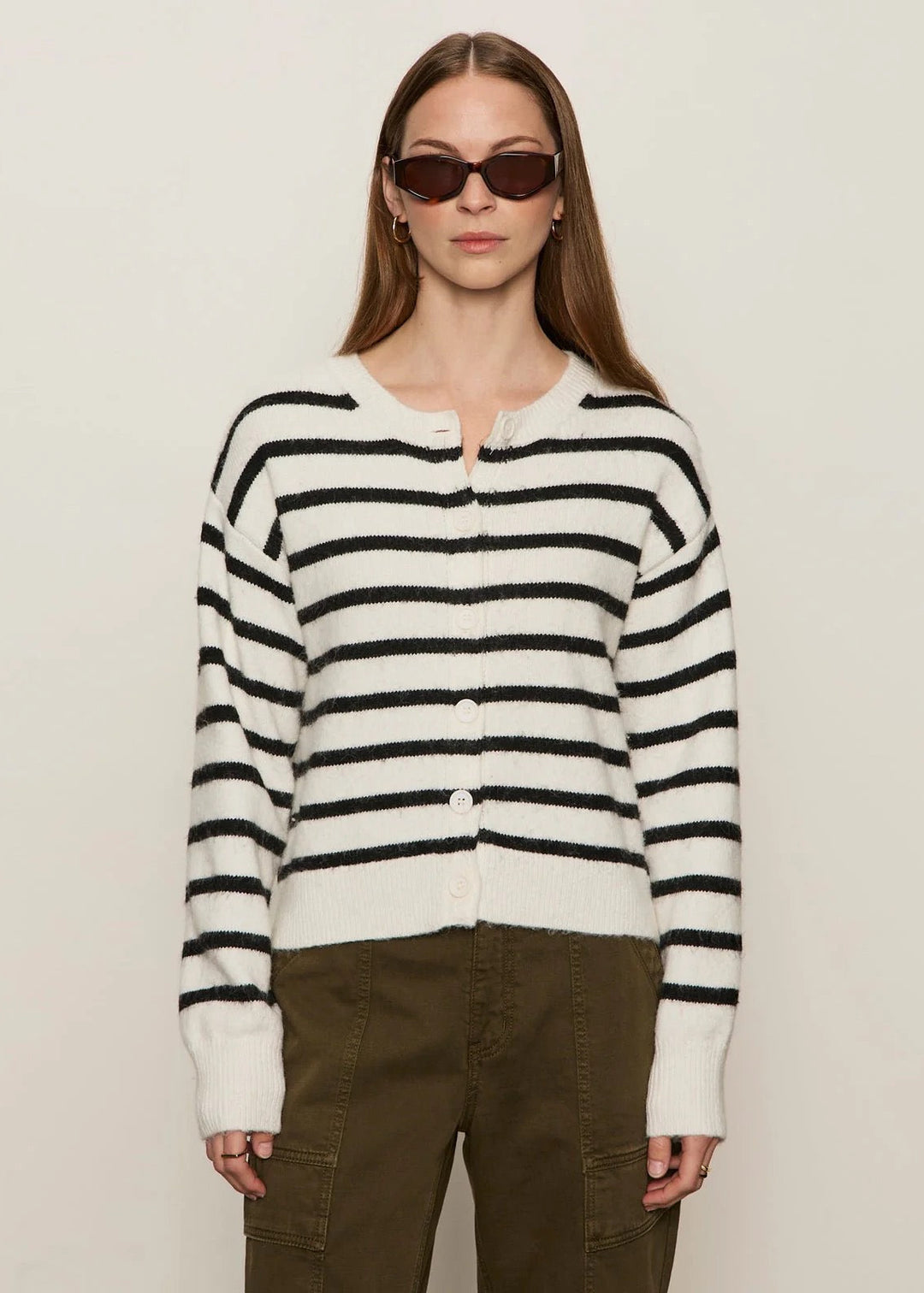Person wearing a black and white striped sweater with brown pants on a plain background