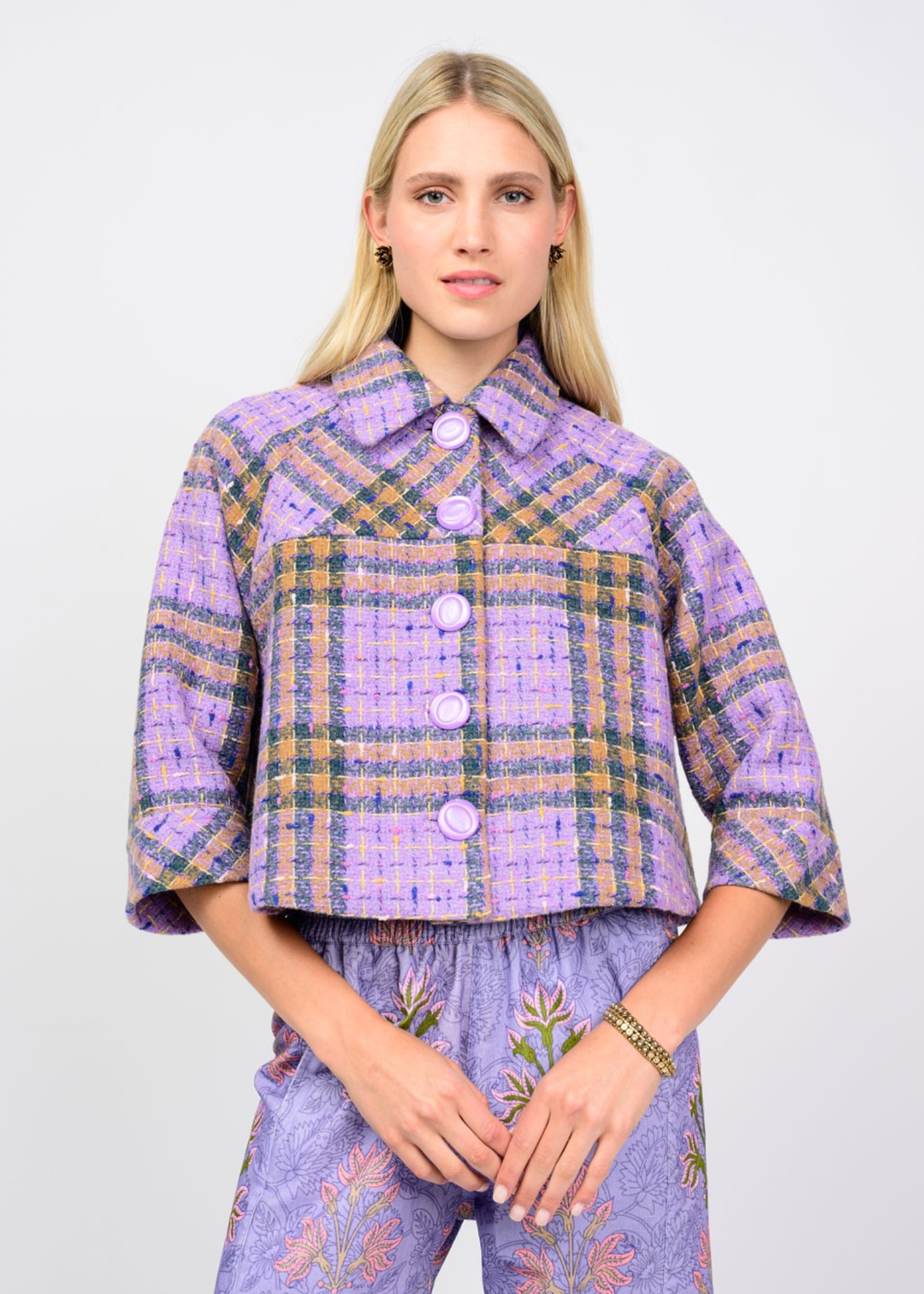 Woman wearing a purple plaid jacket against a white background