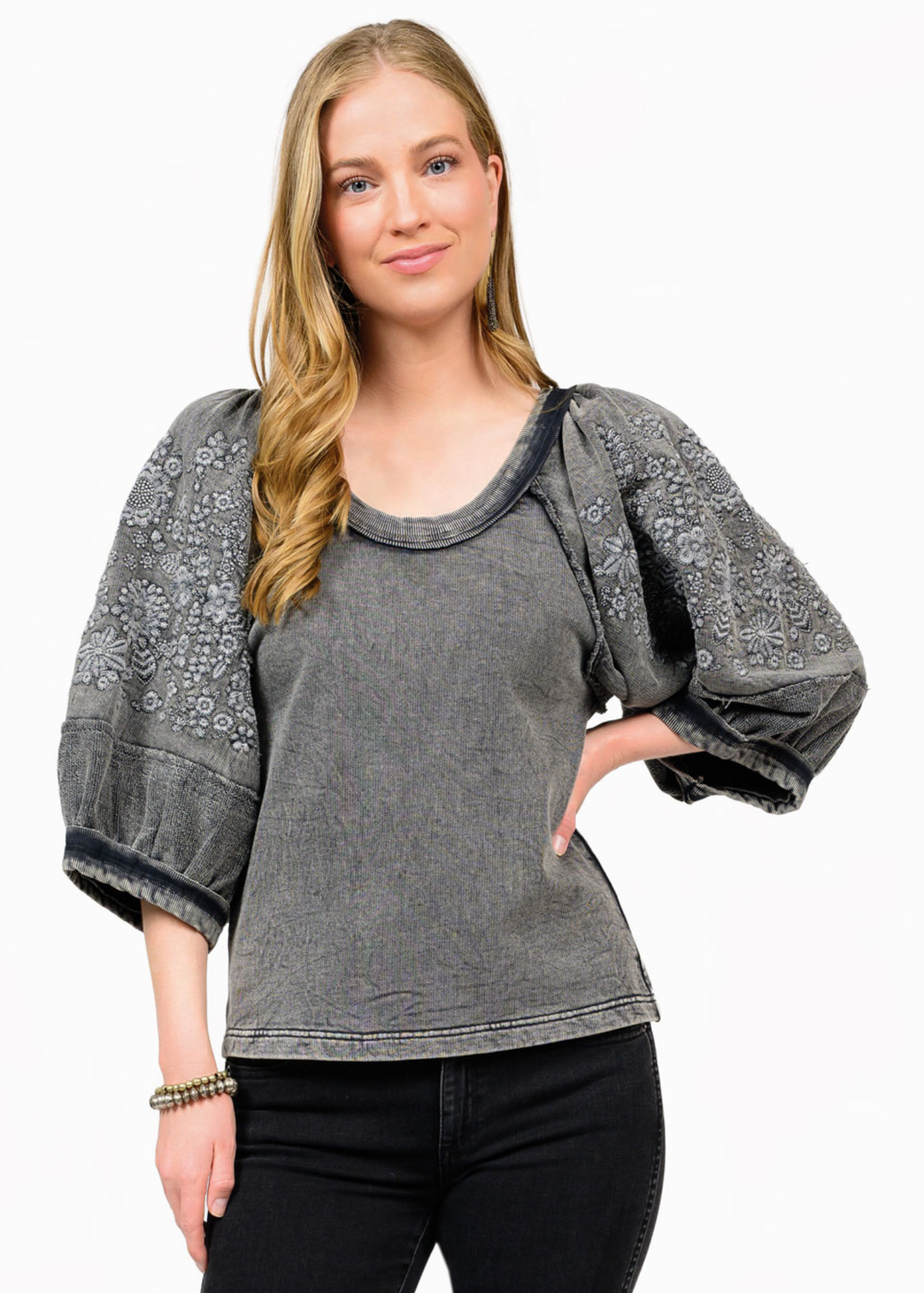 Woman wearing a charcoal top with floral embroidered sleeves