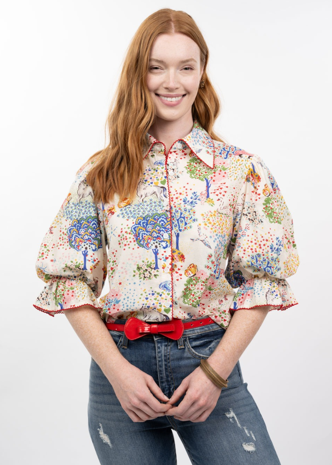 Woman wearing a multicolor patterned button down top with puff sleeves and jeans