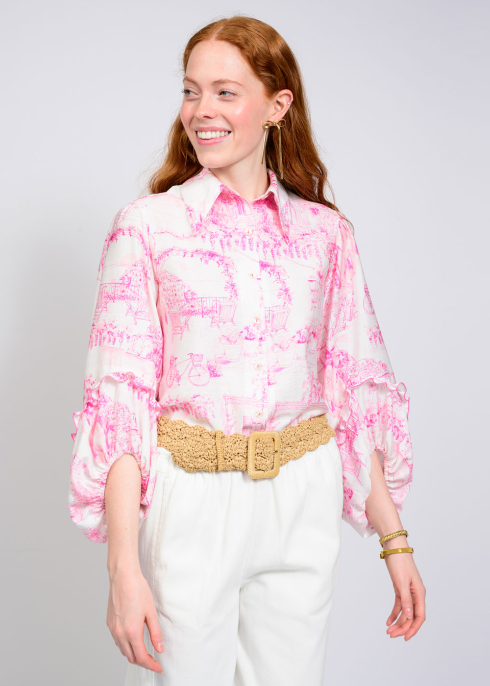 Woman wearing a pink and ivory pattern button down with white pants