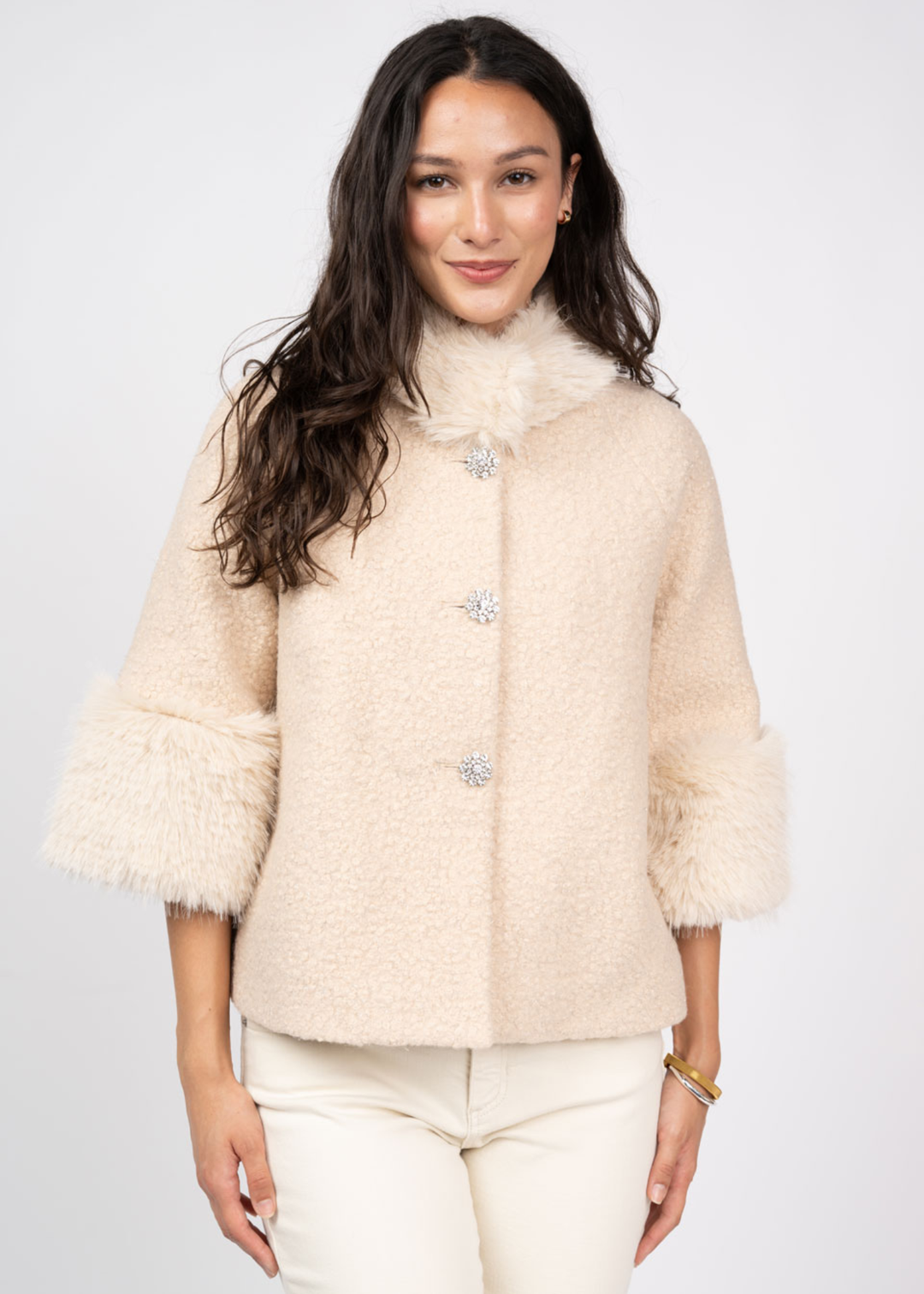 Woman wearing an ivory coat against a white background