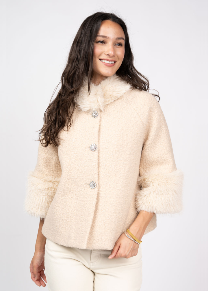 Woman wearing an ivory coat against a white background