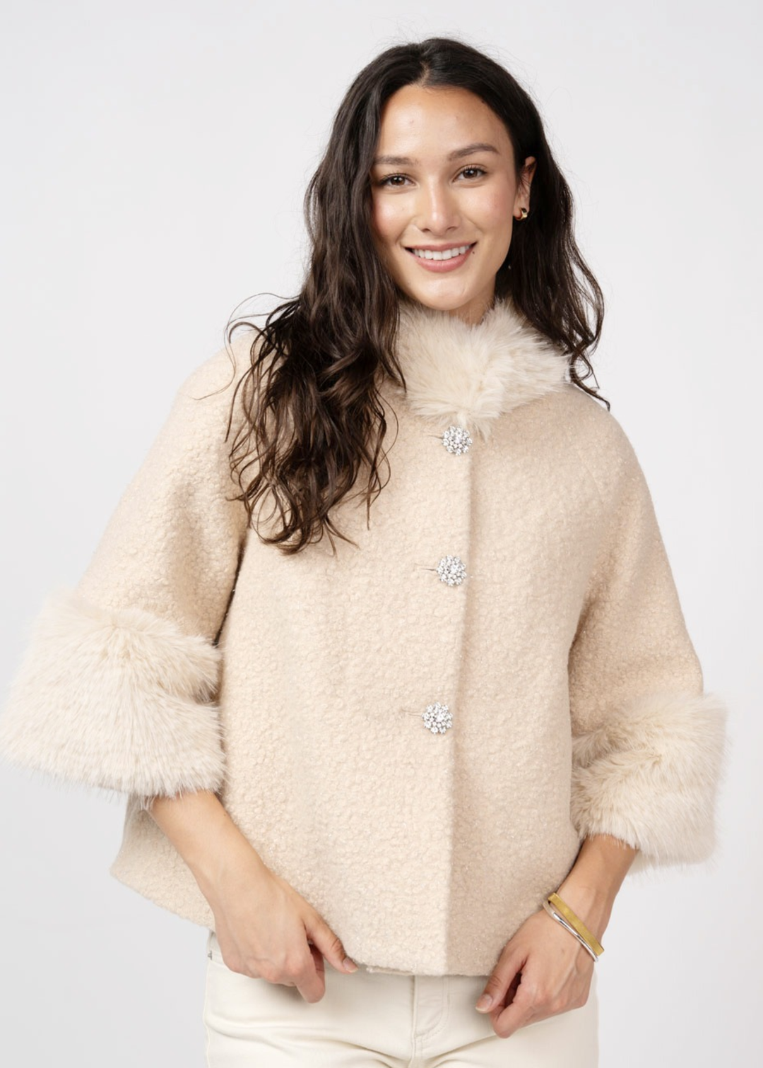 Woman wearing an ivory coat against a white background