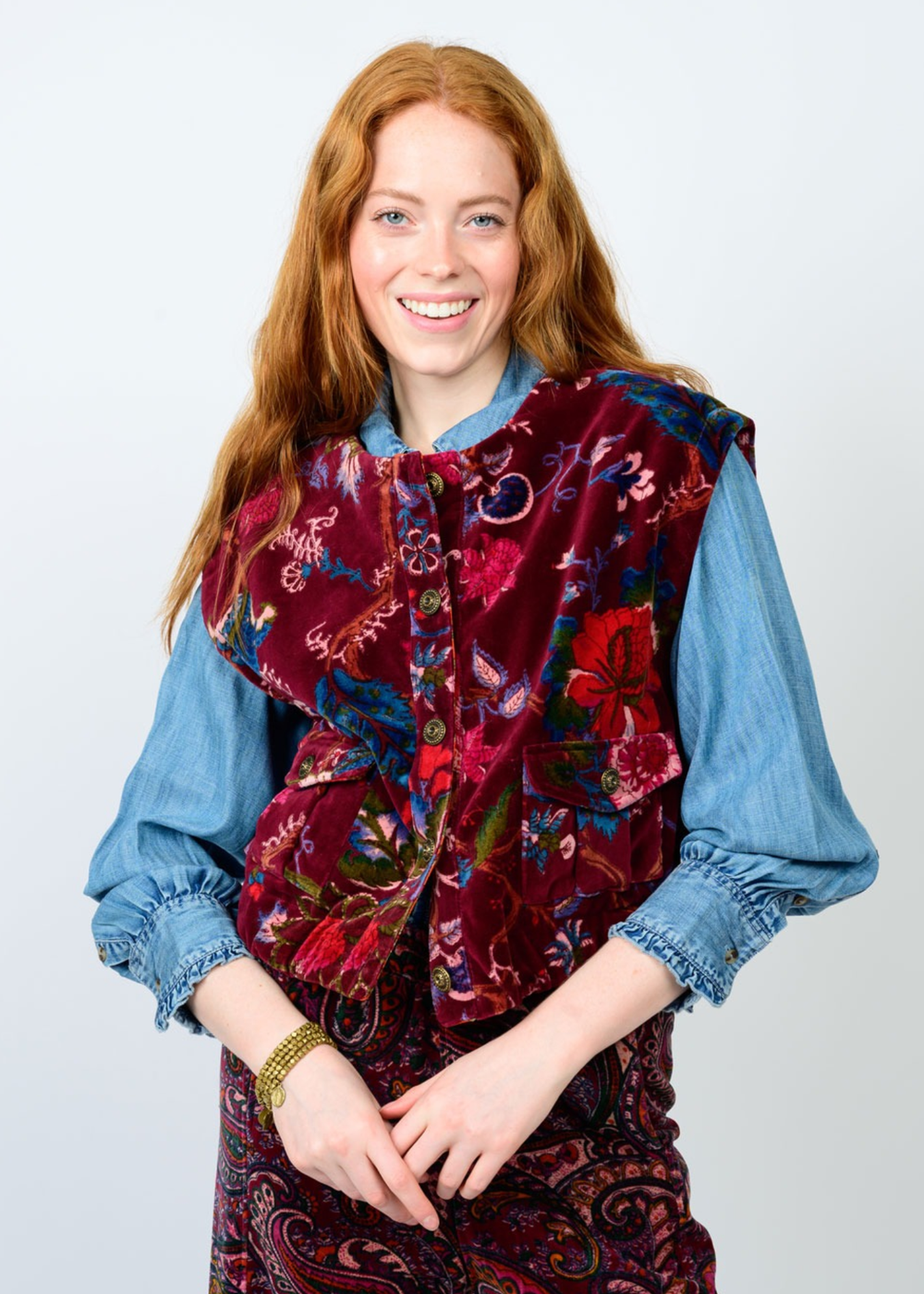 Woman wearing a maroon floral vest against a white background
