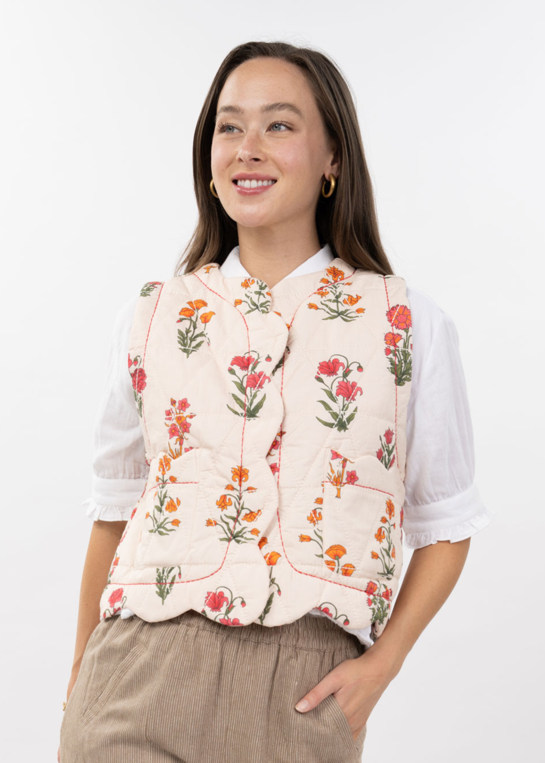 Woman wearing an ivory quilted floral vest with brown pants