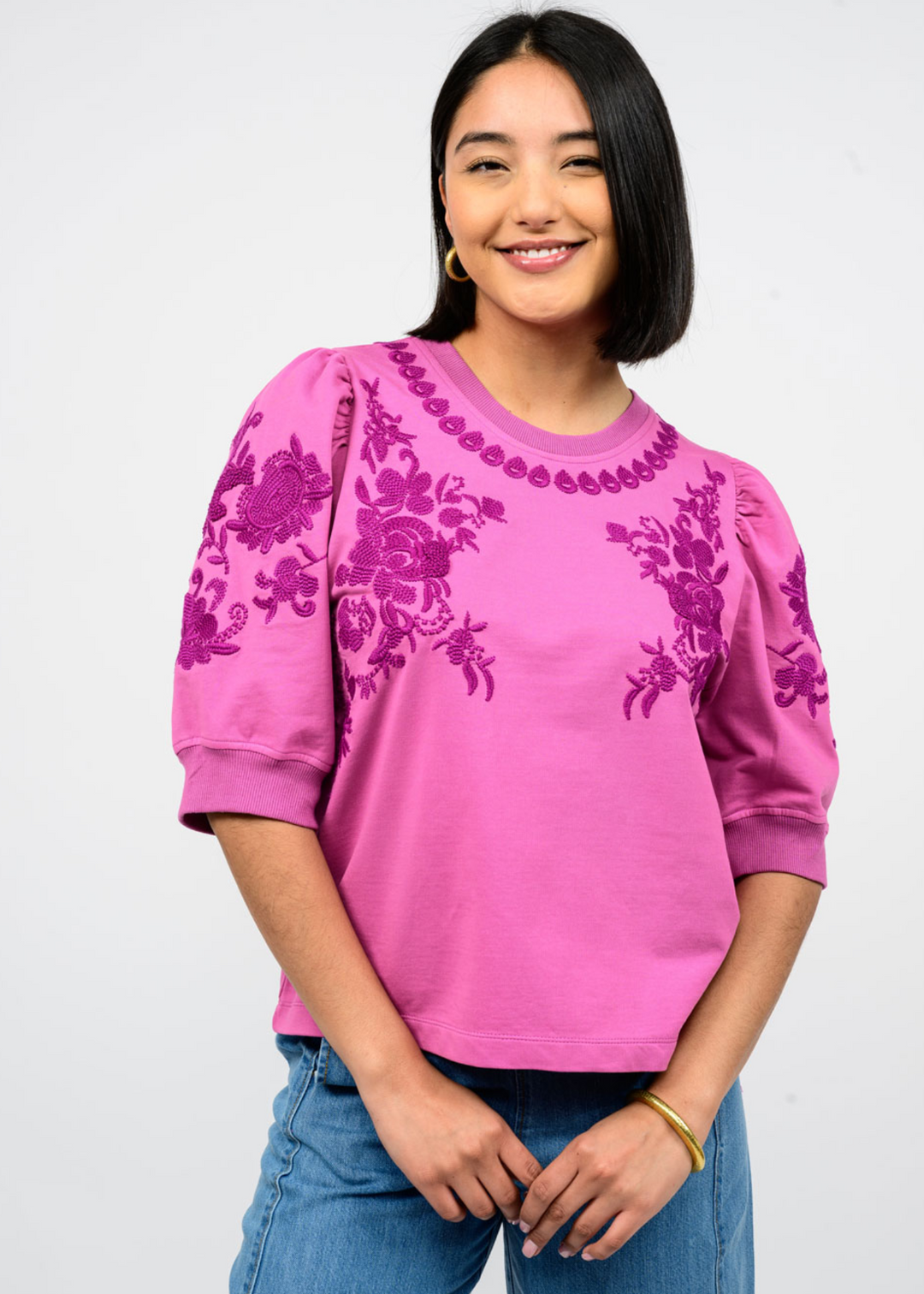 Woman wearing a plum colored top with floral embroidery