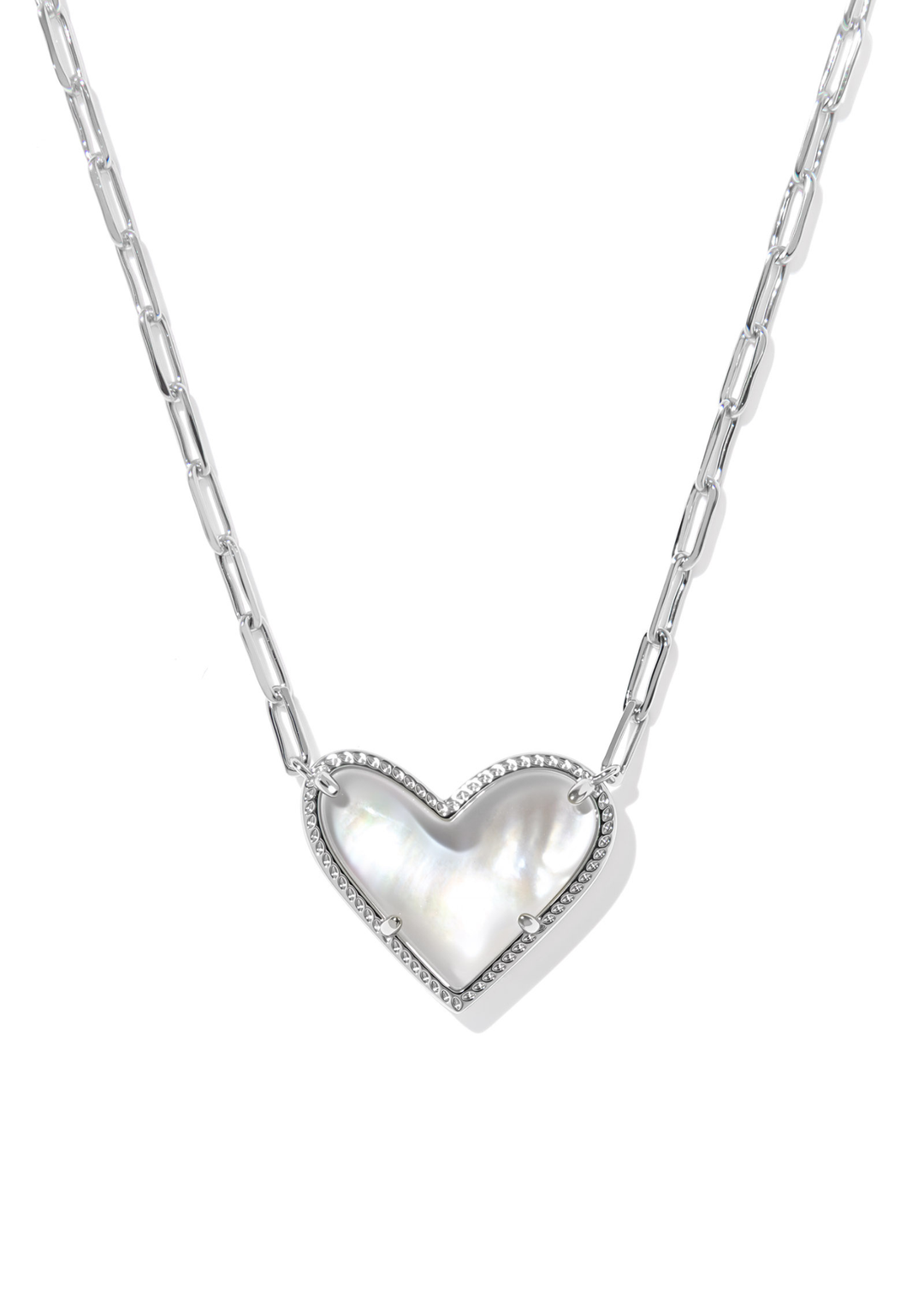 A silver necklace with a silver framed heart shaped pendant with an ivory stone against a white background