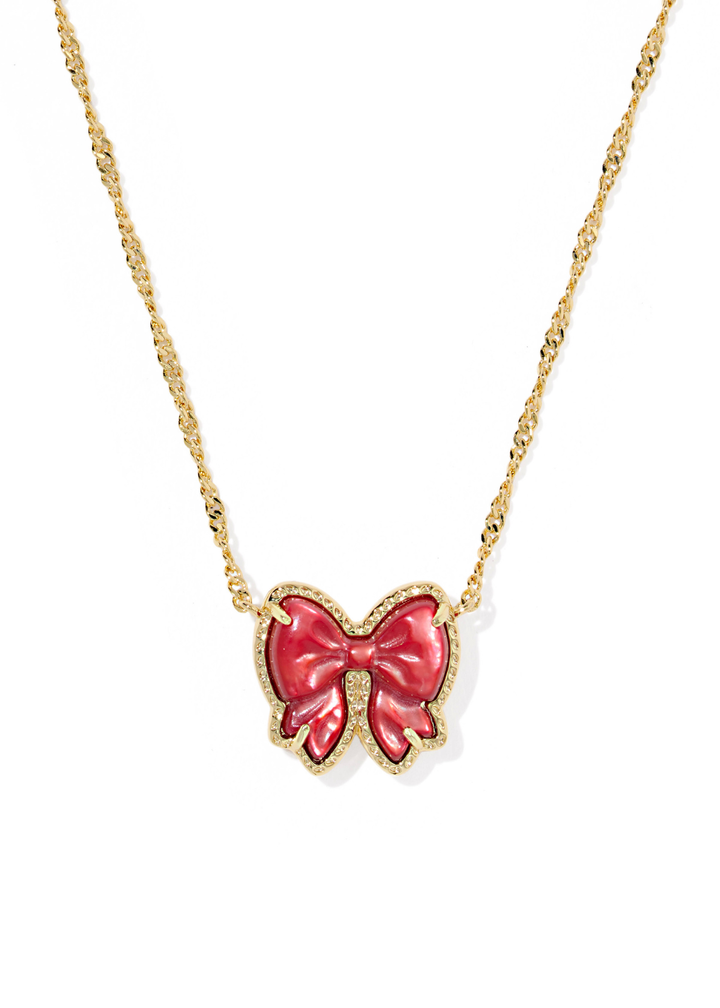 Gold necklace with a red bow pendant on a white background
