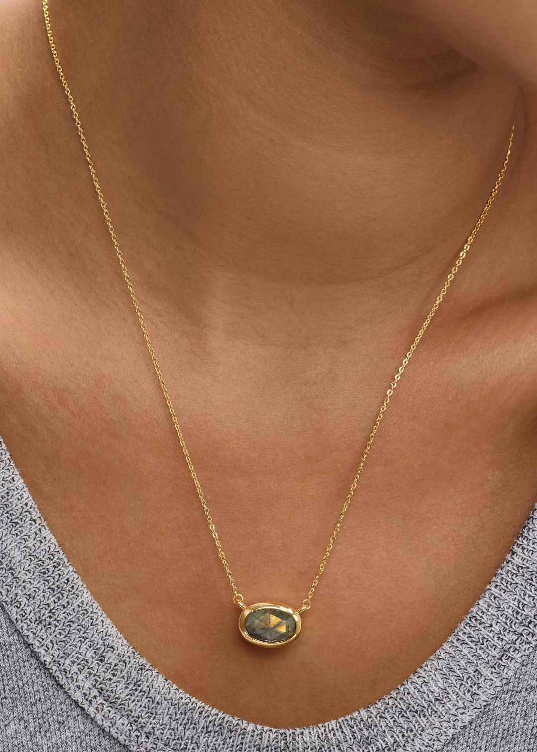 Woman wearing a gold framed labradorite pendant necklace