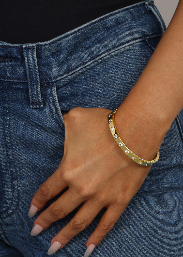 Woman with hand in pocket wearing a gold cuff bracelet with CZ studding