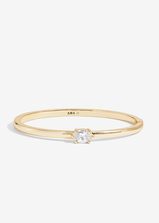 Gold cuff bracelet with a diamond stud on a white background
