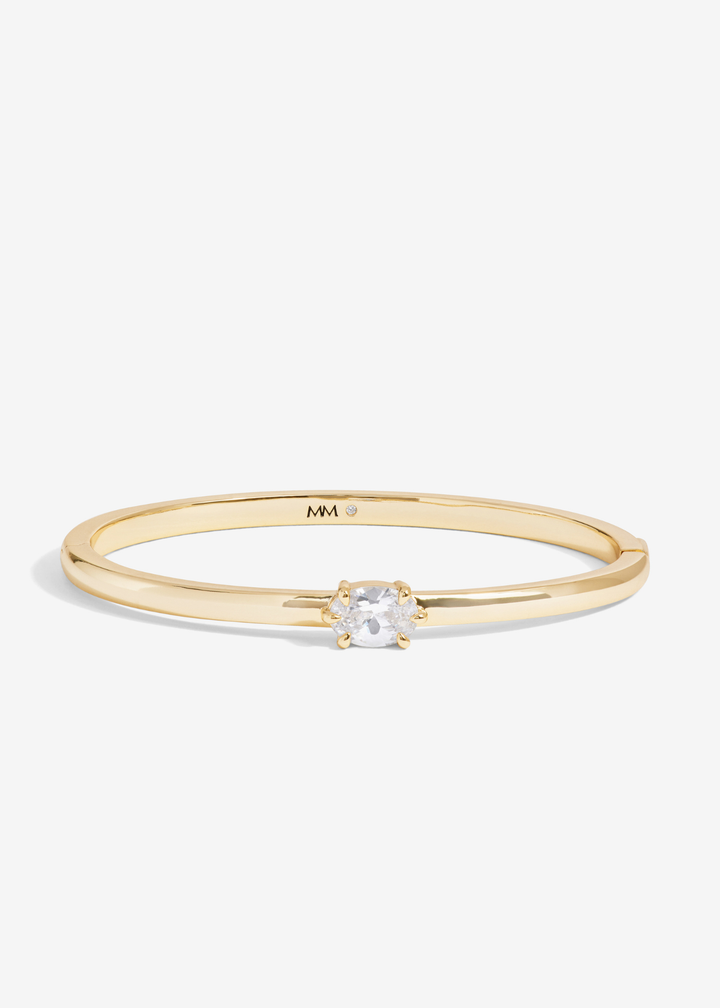 Gold cuff bracelet with a diamond stud on a white background