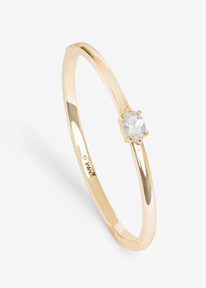 Gold cuff bracelet with a diamond stud on a white background