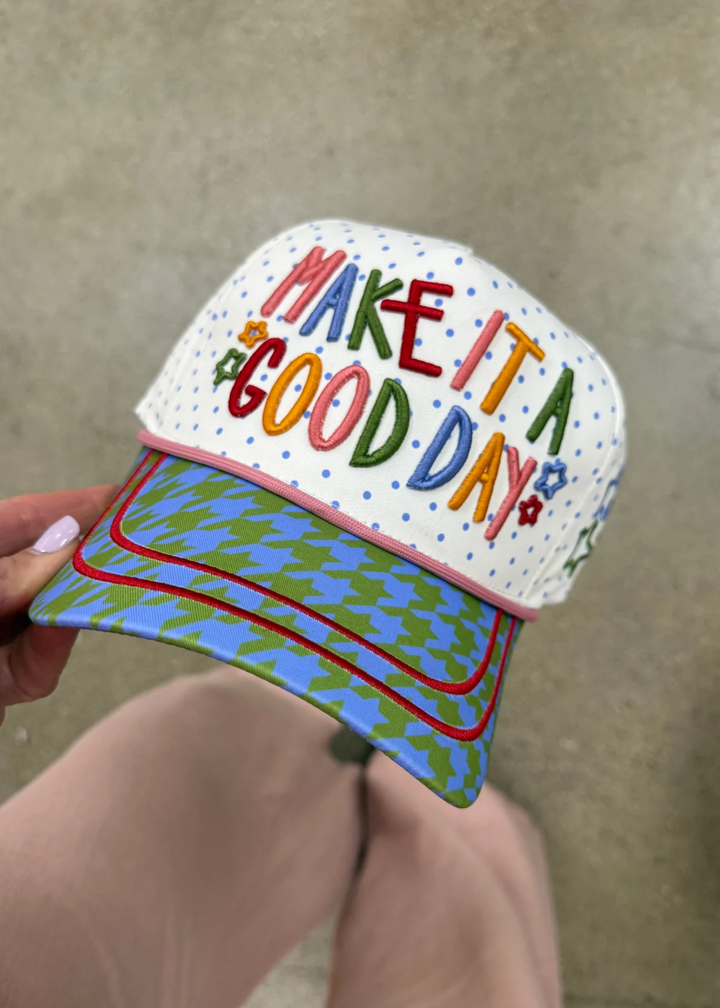 Woman holding a hat with a "Make It A Good Day" graphic