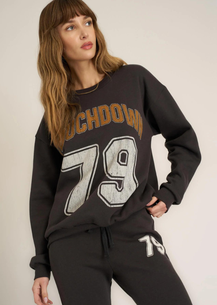 black oversized crew neck sweater with "touchdown" written in gold and white "79" varsity letter graphic on chest