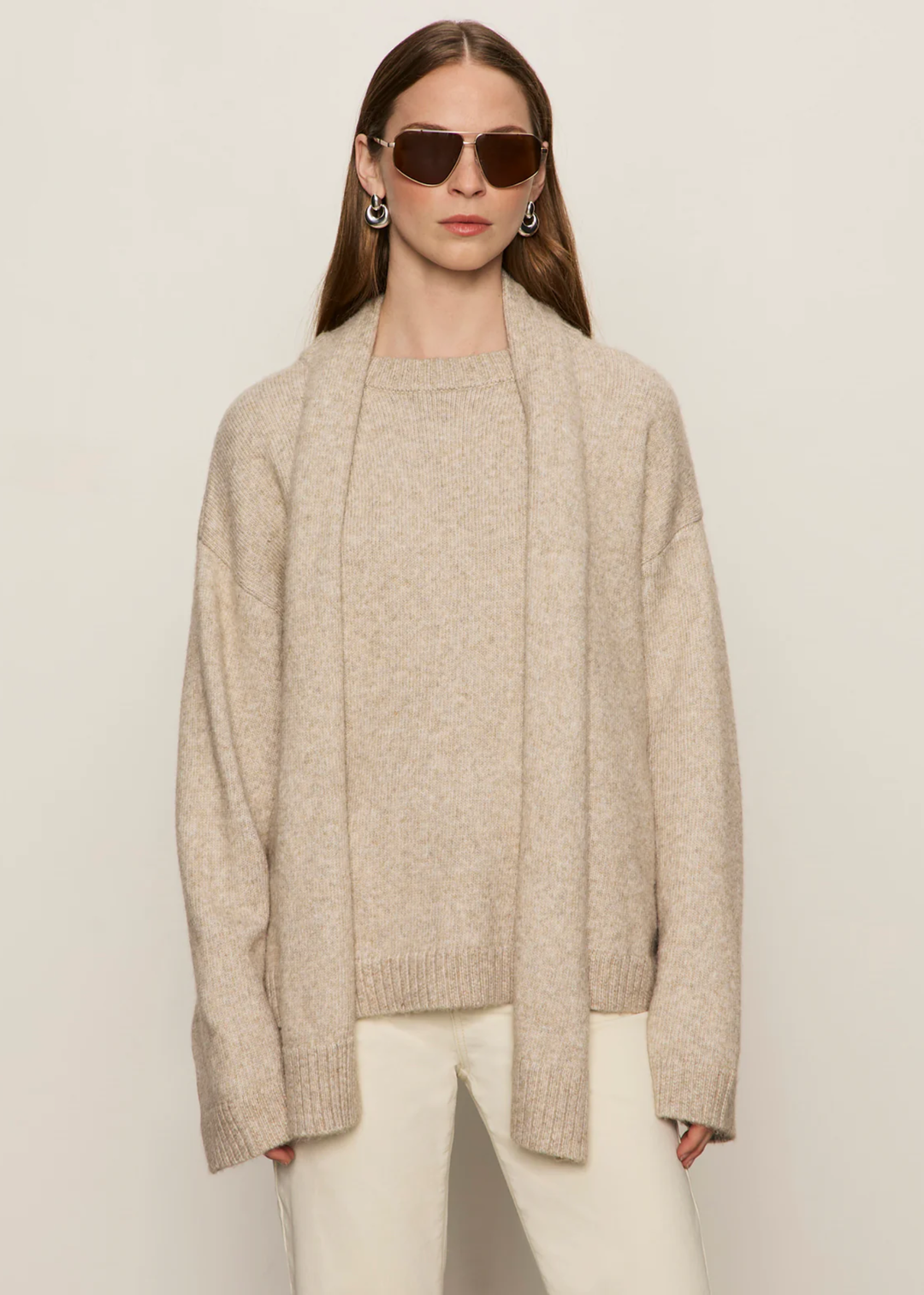 Woman wearing a tan sweater with a tan scarf and cream jeans