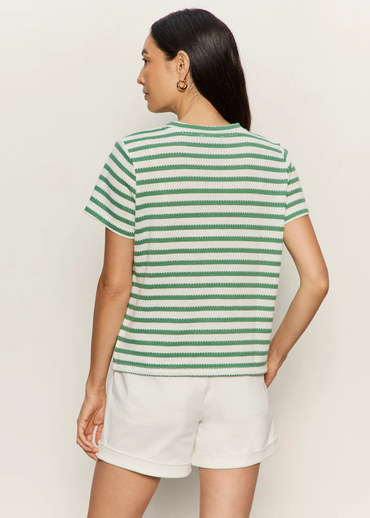 Woman turned around wearing a green and white striped t-shirt with white shorts